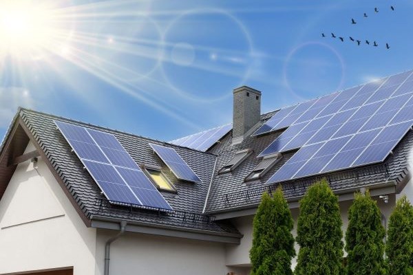 Residential home with solar panel installed on the roof with a solar glare from the sun in the background